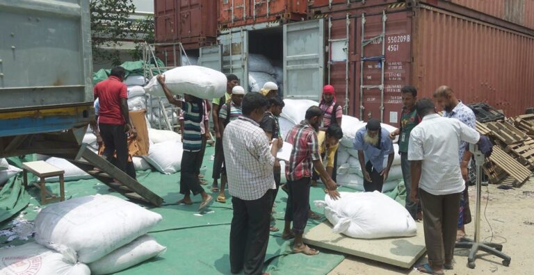 Men loading containers with bags of textile waste