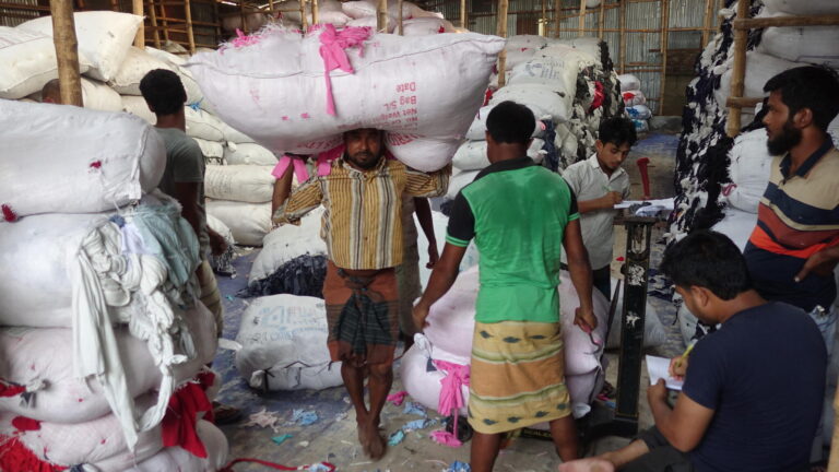 Men carrying bags of textile waste in Bangladesh.